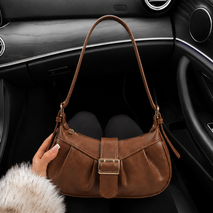 Brown leather handbag on a car seat with a fur coat in the foreground